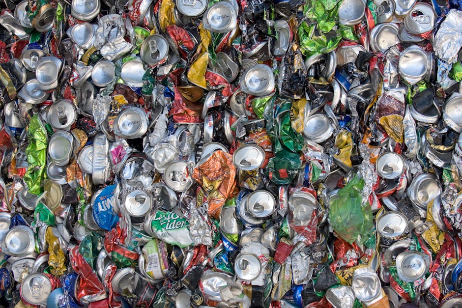 A pile of tightly packed black rubbish bags filled with household waste, including discarded plastic bottles and packaging, situated outdoors against a building wall with beige tiles. The bags are sta